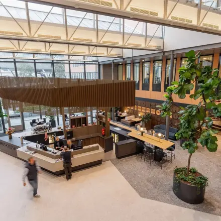 Interior of a modern office space at Jachthavenweg 109, Amsterdam Zuidas, with a reception area and people interacting and working.