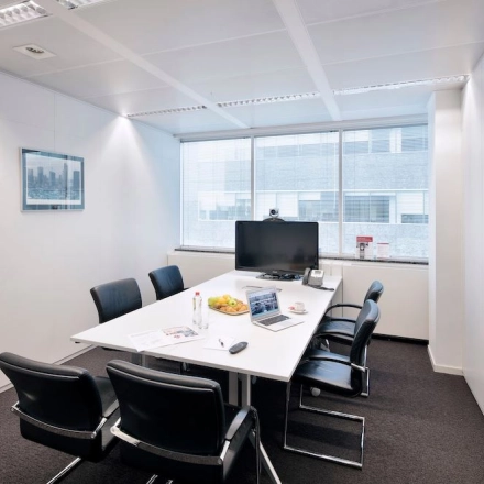Modern conference room available for office space rental at Lange Lozanastraat 142, Antwerp Center, featuring a sleek table, black chairs, and a large screen.
