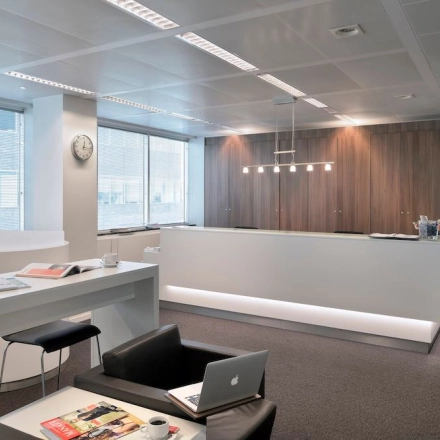 Modern office space with sleek furnishings at Lange Lozanastraat 142, Antwerp Center, perfect for office space rental. Features a long white desk and lounge chairs.