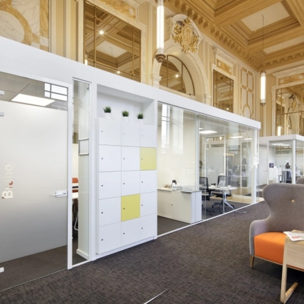 Elegant office space rental at Pelikaanstraat 3, Antwerp Center with glass-partitioned workspaces and comfortable seating.
