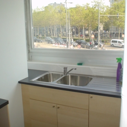 Office space rental with a kitchenette at Amerikalei 78A, Antwerpen Zuid, featuring a double sink beneath a window with city views.