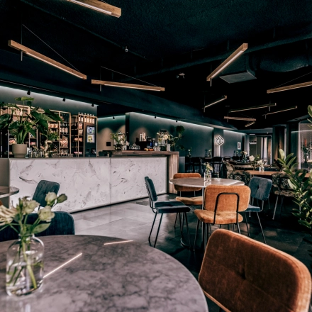 Stylish office space in Apeldoorn with modern furnishings, including round tables, chairs, and plants. Suitable for rent office space or office space rental.