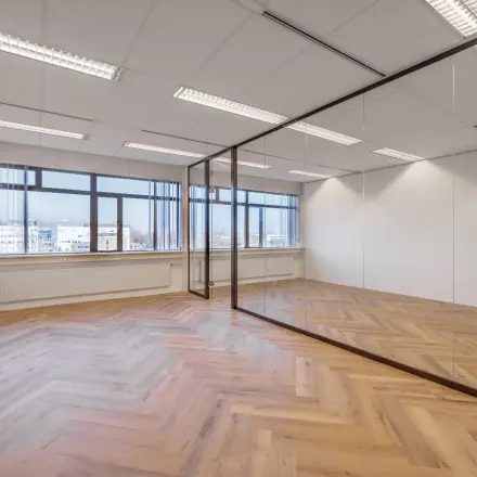 Spacious office for rent at Oude Apeldoornseweg 41-45, Apeldoorn featuring large windows and a wooden floor.