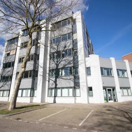 Exterior view of an office building at Prins Willem-Alexanderlaan 401, Apeldoorn, ideal for those seeking office space rental. Features a modern facade with adjacent parking spaces.