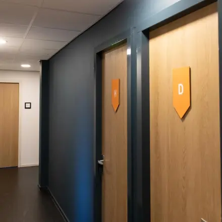 Hallway of an office space to rent at Prins Willem-Alexanderlaan 401, Apeldoorn, featuring a sleek, modern design with wooden doors and a dark wall finish.