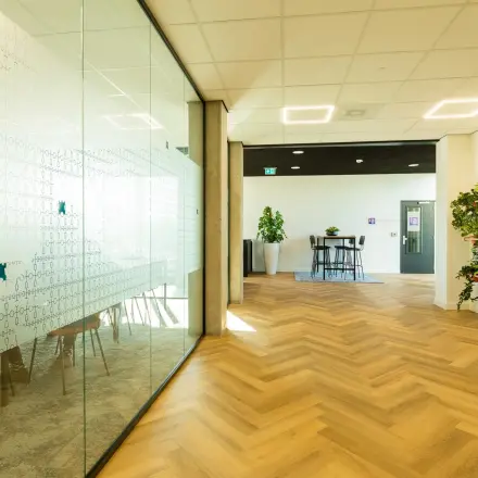 Bright office to rent at Prins Willem Alexanderlaan 701, Apeldoorn, featuring large glass partitions and wooden flooring ideal for renting office space.