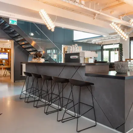 Modern office space for rent in Apeldoorn at Roggestraat 111 featuring a sleek bar area with stools and contemporary lighting.