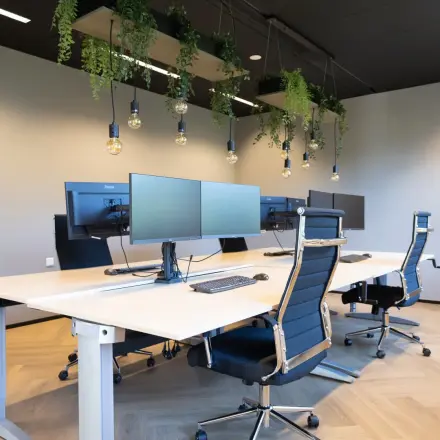 Modern furnished office space with desks and chairs at Schumanpark 9, Apeldoorn, available for rent. Ideal for collaborative work in a sleek setting.
