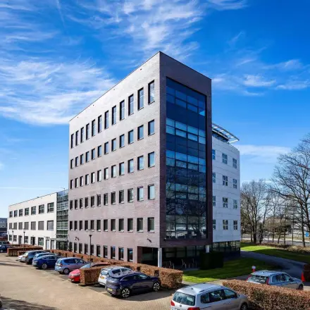 Exterior view of an office building at Schumanpark 9, Apeldoorn, suitable for office space rental, with ample parking space visible.