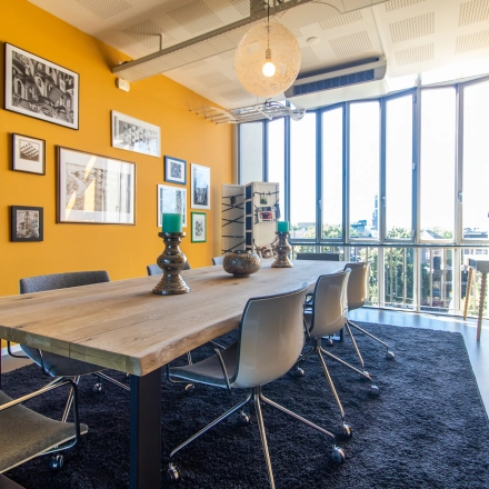 Bright office to rent at Jansbuitensingel 7, Arnhem Centrum, featuring a furnished meeting area with large windows and vibrant decor.