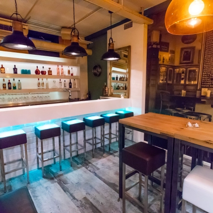 A modern office lounge in Arnhem Centrum at Jansbuitensingel 7, featuring a stylish bar setup with high stools and ambient lighting, ideal for rent office space activities.
