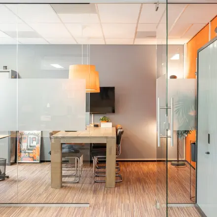 Modern office space to rent at Vlamoven 34, Arnhem IJsseloord, featuring a stylish meeting area with glass walls and warm lighting.