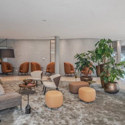 Stylish lounge area in Arnhem Zuid with modern seating and lush plants, ideal for office space rental.