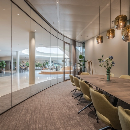 Modern conference room with glass walls, surrounded by a lush, open-floor work area. Ideal for office space rental at Rijksweg-West 2, Arnhem Zuid.