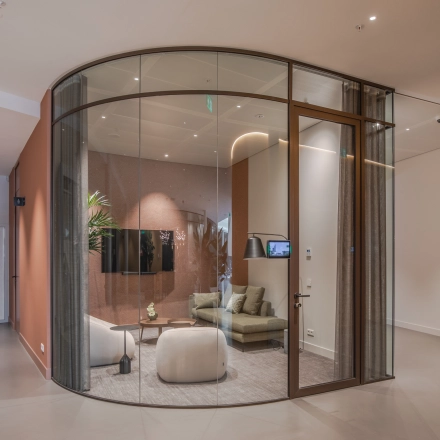 Contemporary furnished office space for rent at Rijksweg-West 2, Arnhem Zuid, featuring a glass-enclosed meeting area with modern seating and plants.