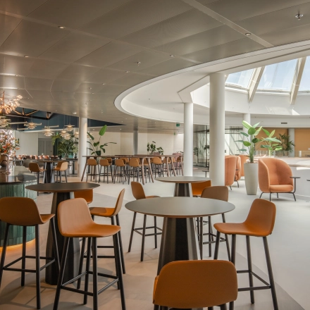 Spacious, modern workspace with round tables and chairs under a skylight, ideal for office space rental in Arnhem Zuid.