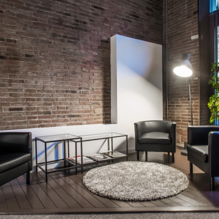 Inviting office space with modern furnishing, including three black chairs and a round rug, located in Barcelona Eixample. Ideal for office space rental with a touch of style.