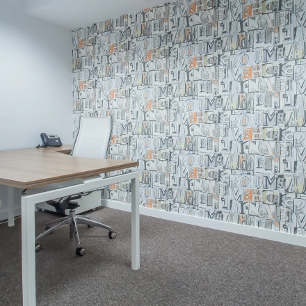 Cozy office space with modern furnishings, including a wooden desk, chairs, and a decorative wall at Carrer d'Aribau 161, Barcelona Eixample. Ideal for office space rental.