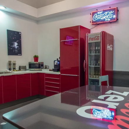 Bright kitchen area in an office space rental with red cabinets and Coca-Cola branding, located at Carrer d'Aribau 161 in Barcelona Eixample.