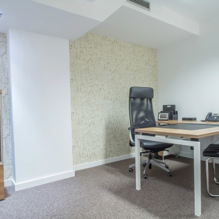 A furnished office space with a desk, chair, lamp, and potted plant at Carrer d'Aribau 161 in Barcelona Eixample, ideal for rent office space needs.