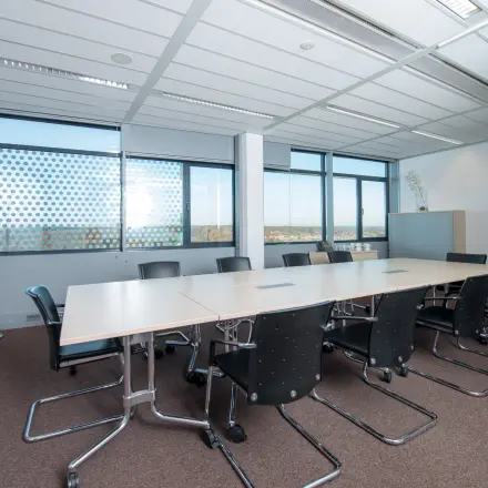 Spacious conference room at Carrer de la Marina 16-18, Barcelona Sant Martí, featuring a long table with black chairs, ideal for office space rental.