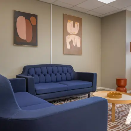 Cozy office space featuring blue sofas, modern artwork, and a small coffee table, available for rent at Kamerlingh Onnesweg 10 in Barendrecht.