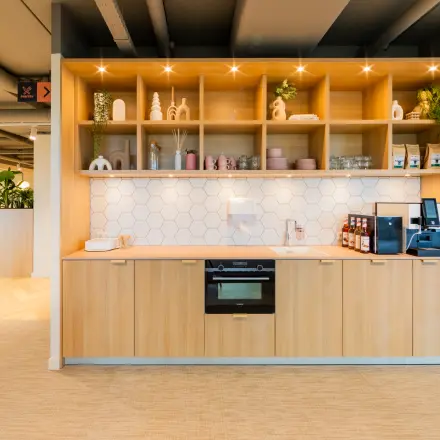 Bright office pantry with wooden cabinetry, coffee machine, and decorative shelves offering comfortable office space rental at Baron van Nagellstraat 136, Barneveld.
