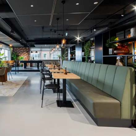 Modern office space with stylish furnishings, featuring a long green bench and tables, available for rent at Baron van Nagellstraat 136 in Barneveld.