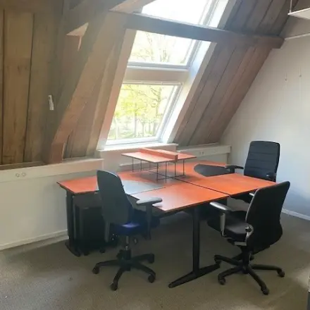 Bright office to rent at Blokstallen 2B, Bergen op Zoom, featuring wooden beams and desks beneath a large skylight, ideal for business activities.