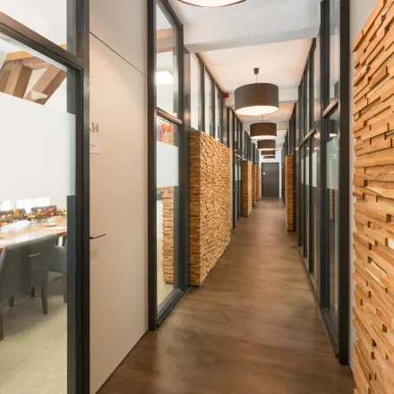 Modern office hallway at Blokstallen 2B, Bergen op Zoom with wooden paneling and glass-walled meeting rooms available for rent. Ideal office to rent for business operations.