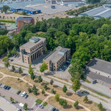 Aerial view of office buildings for rent at Rijtuigweg 10, Bergen op Zoom, surrounded by greenery and near a waterway, offering potential office space rental opportunities.