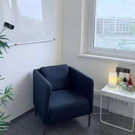 Cozy office corner at Markgrafendamm 24, Berlin Friedrichshain, featuring a chair, side table, and whiteboard. Perfect office space rental opportunity.