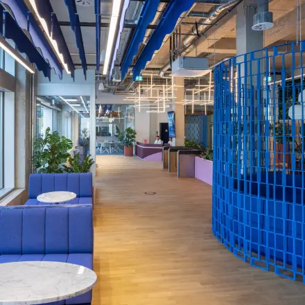 Brightly colored office space with blue seating and tables next to large windows, suitable for rent office space at Heidestraße 34, Berlin Mitte.