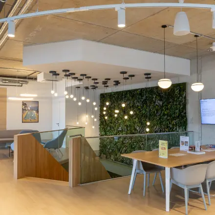 Modern workspace with a green wall, a wooden table, and seating area at Heidestraße 34, perfect for office space rental.