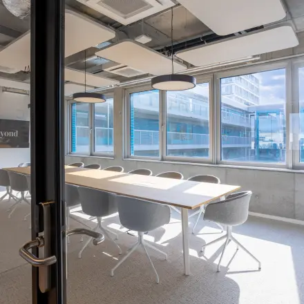 Bright conference room at Heidestraße 34, Berlin Mitte with modern furnishings, large windows, and a long table for office space rental.