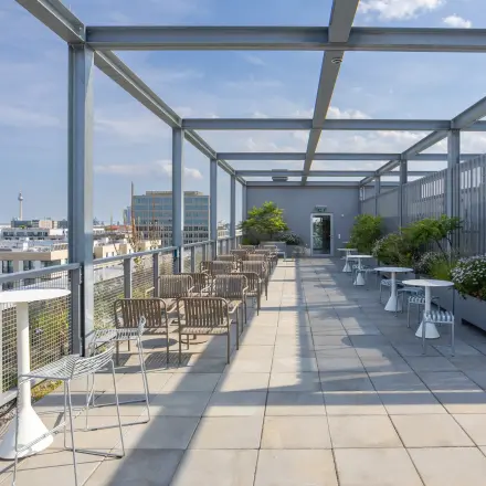 Spacious rooftop terrace at Heidestraße 34, Berlin Mitte, featuring tables and chairs ideal for open-air meetings, perfect for those looking to rent office space with stunning city views.