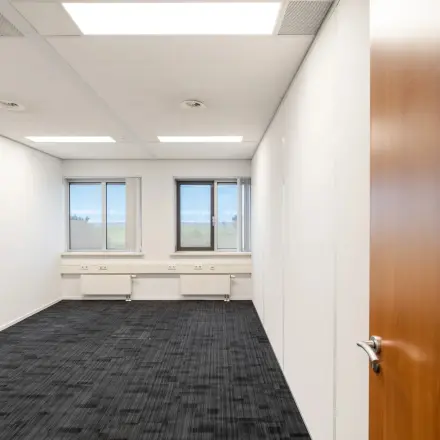 Bright and empty office space available for rent at Tolnasingel 1 - 3, Bodegraven. Features carpeted floors and large windows.