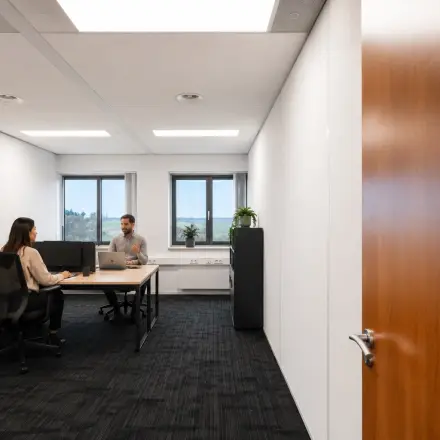 Office space rental in Tolnasingel 1 - 3, Bodegraven, featuring two professionals engaged in a meeting around a shared desk, highlighting an inviting workspace environment.