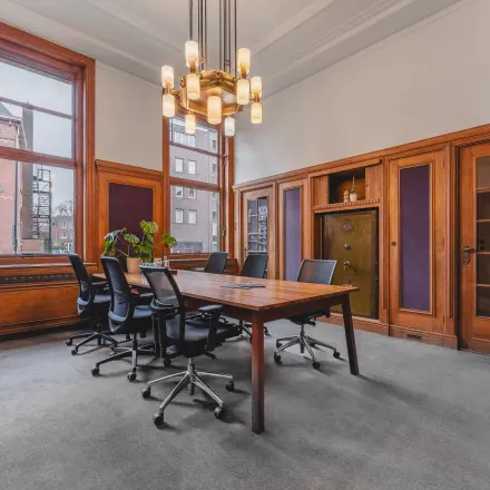 Office space for rent at Ceresstraat 13, Breda Centrum-Station, featuring a furnished meeting room with a large wooden table and chairs, surrounded by wooden paneling and large windows.