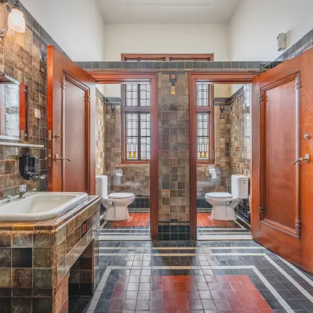 A restroom at Ceresstraat 13, Breda Centrum-Station featuring a vintage tile design and wooden doors, suitable for office space rental needs.