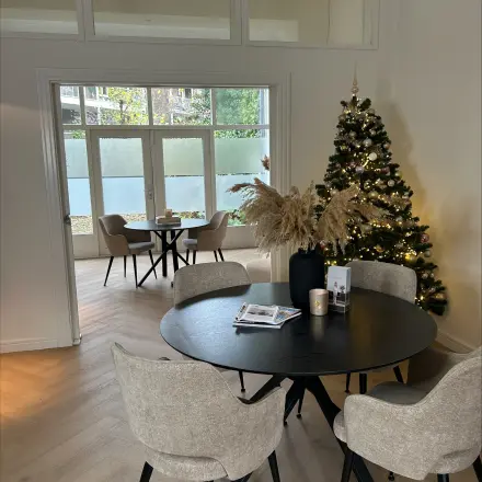 Cozy and inviting office space with a decorated Christmas tree, ideal for rent in Breda Centrum-Station, featuring a round table and chairs, perfect for meetings.
