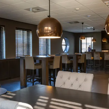 Furnished office space for rent at Takkebijster 57A, Breda Oost-Brabantpark, featuring comfortable seating, modern lighting, and a bar area. Ideal for collaborative workspaces or open meetings.