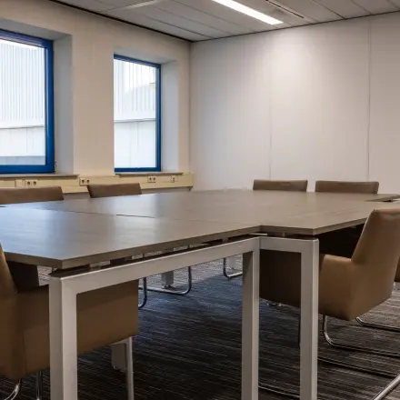 Spacious conference room with brown chairs around a large table, located at Takkebijster 57A, Breda Oost-Brabantpark, ideal for office space rental.