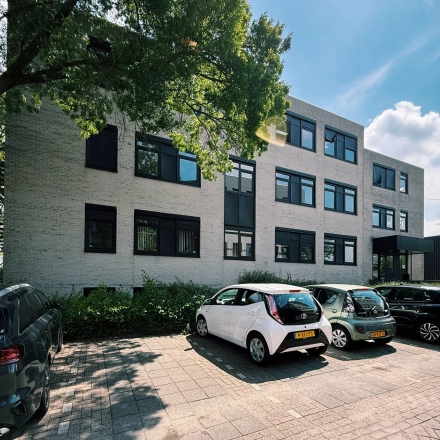 Exterior view of an office building at Druivenstraat 25-31 in Breda Oost, with cars parked in front, ideal for office space rental.