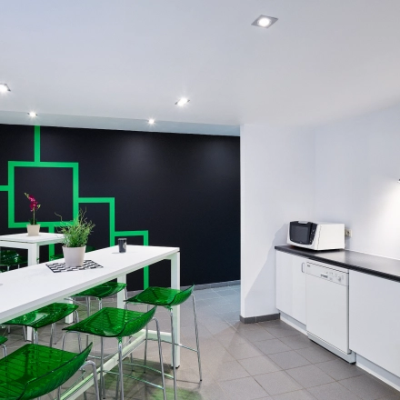 Bright office space rental with a modern kitchenette and vibrant green seating, ideal for breaks and informal meetings at Brussels Airport. Available to rent office space at Leuvensesteenweg 613.