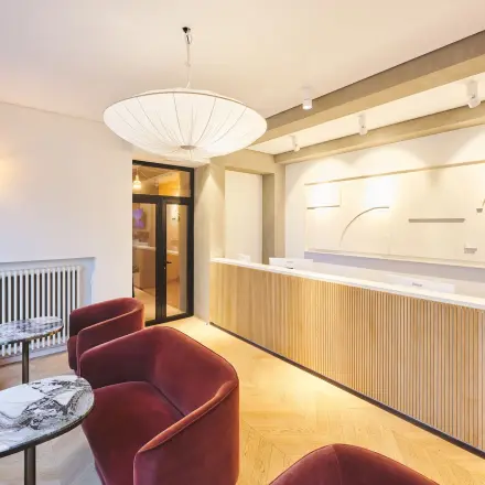Modern reception area with a wooden desk and stylish red chairs, ideal for renting office space in Brussels Center.