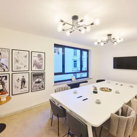 Modern conference room at Rue du Congres 37, Brussels Center, ideal for office space rental, featuring a long table, chairs, and wall art.