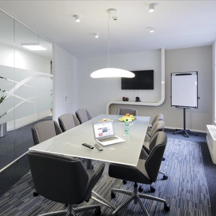 Modern office space with a glass wall, meeting table, chairs, TV, and flipchart in Avenue Louise, Brussels. Perfect for office space rental.