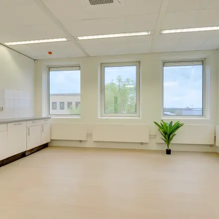 Available office space for rent at Regulierenring 2, Bunnik, featuring large windows and a kitchenette area, ideal for creating a comfortable workspace.