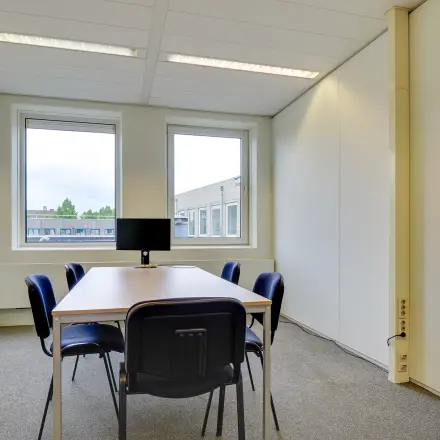 Bright office space at Regulierenring 2, Bunnik, featuring a table with chairs and a monitor in a well-lit environment, ideal for rent office space.